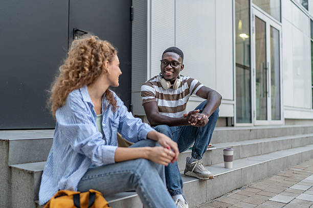 istock Students talking and smiling on university campus stairs 2239999609