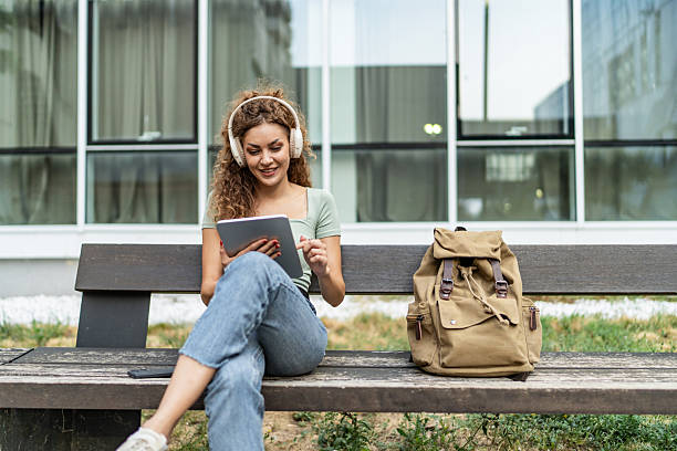 istock Young woman studying with tablet and headphones on campus bench 2239999799