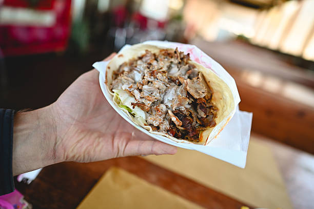 istock Hand holding savory doner kebab or shawarma wrap 2240000330