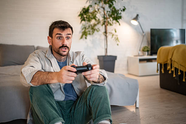 istock Man playing expressive video game at home 2240001849