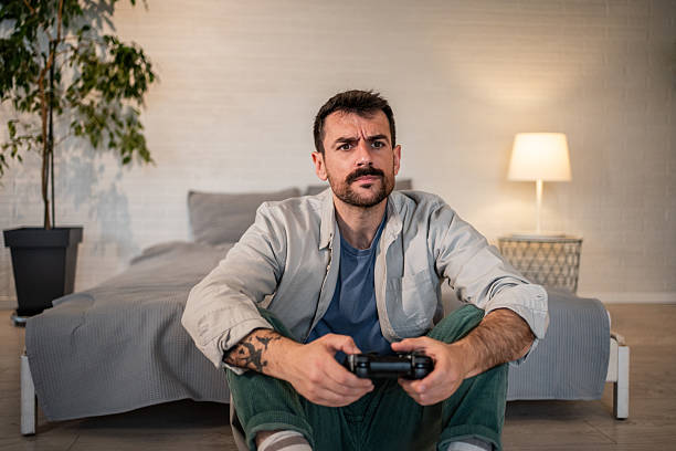 istock Young adult man playing video game at home 2240001929