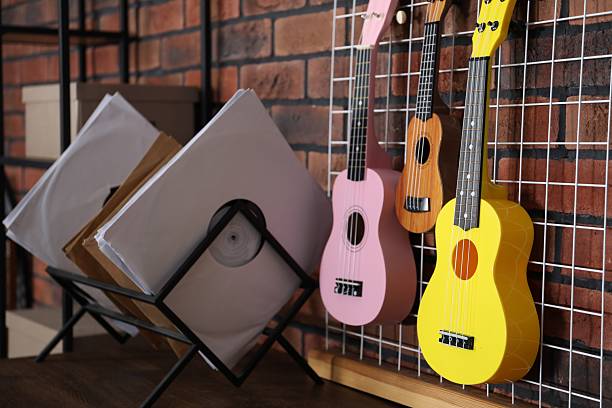 Three colorful ukulele on brick wall and records indoors