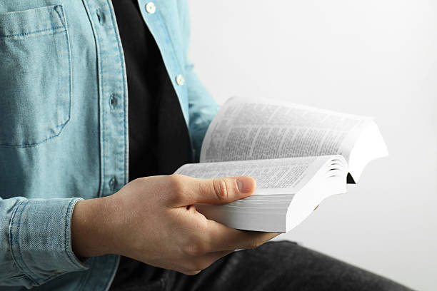istock Man reading Holy Bible on light background, closeup 2240003197