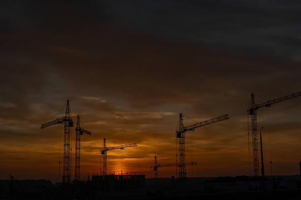 istock Silhouettes of construction cranes on a building site 2240004773