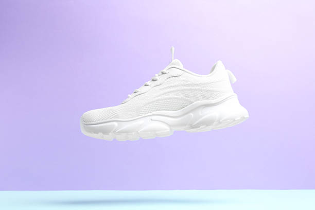 istock Stylish white sneaker in air against color background 2240005491