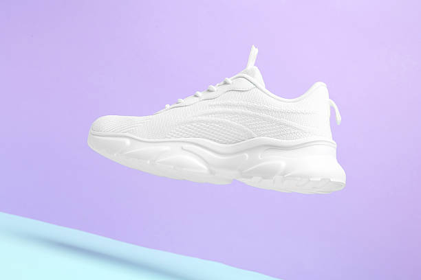 istock Stylish white sneaker in air against color background 2240005602