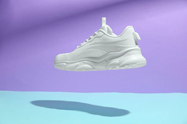 istock Stylish white sneaker in air against color background 2240005630
