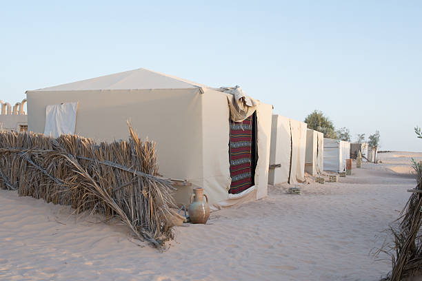 Dunes in Wahiba desert in Oman, in distance some settlements, desert village and blue sky.