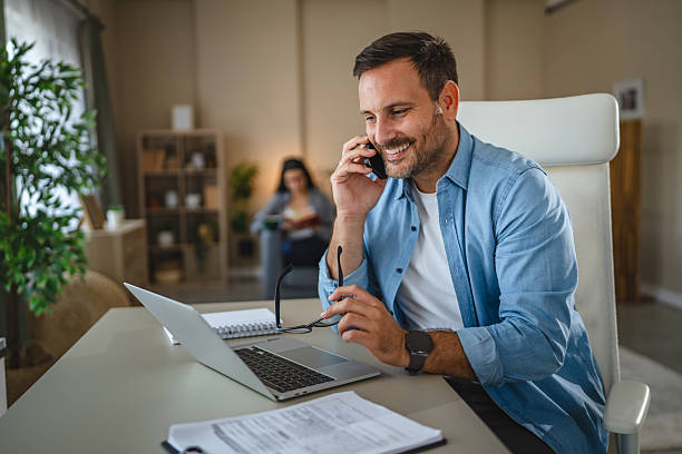 istock Smiling man talking on phone working in home office 2240006691