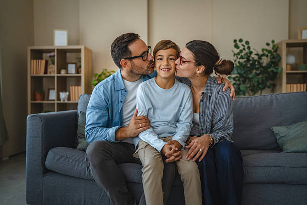 istock Parents kissing happy son on sofa at home 2240006742