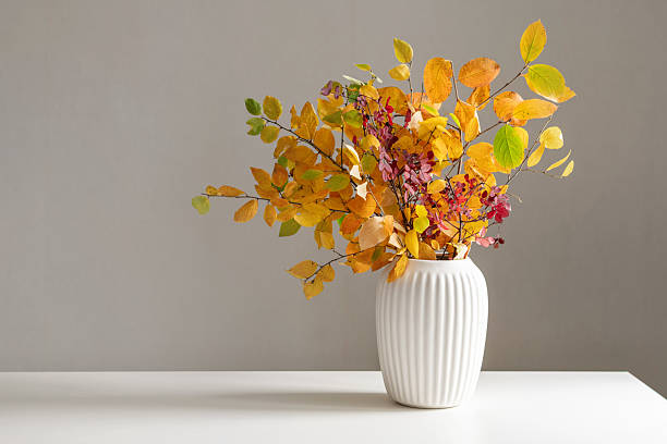 istock Dry fall leaves and branches in white vase. Season home interior. 2240007830