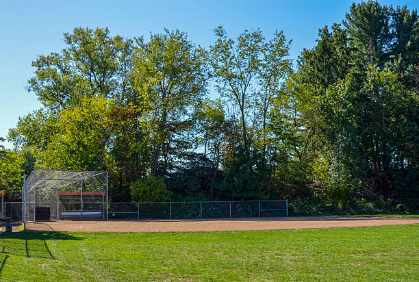 istock Empty baseball field with dugout and green trees 2240010250