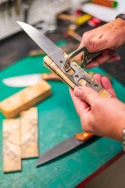 Close-up photo of man hand sharpening knives with special knife sharpener at table kitchen in the home