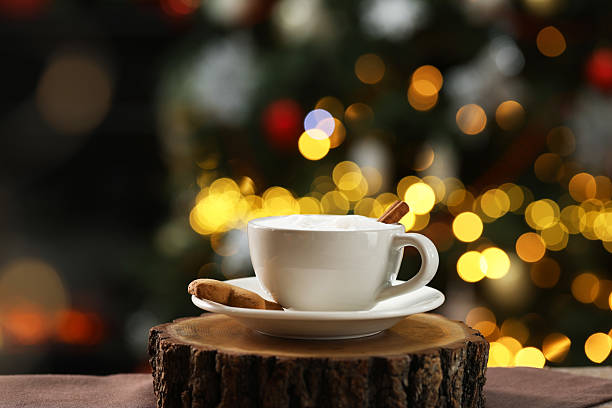 Aromatic coffee in cup and tasty cookie on table against blurred Christmas lights, bokeh effect