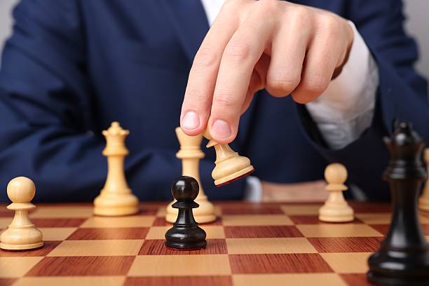 istock Businessman playing chess on chessboard against light grey background, closeup. Competition concept 2240012880