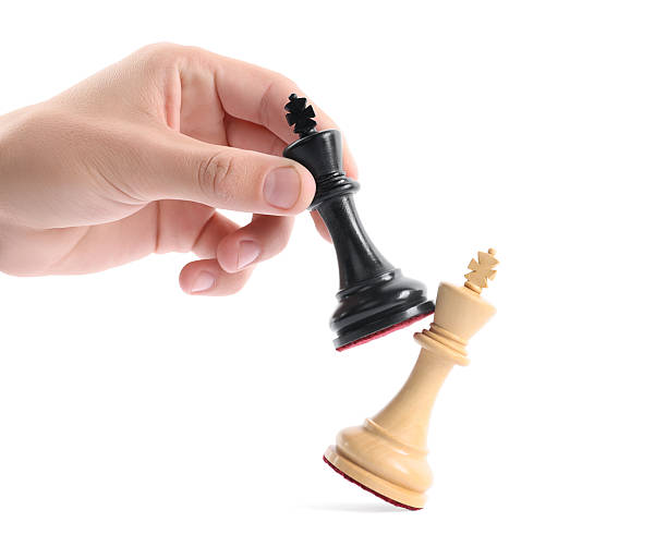 istock Man with black chess king knocking over white one on white background, closeup. Competition concept 2240012915