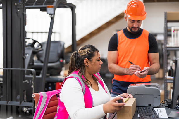 istock Team calculating dimensions and labeling packages, entering order details on computer. 2240015694