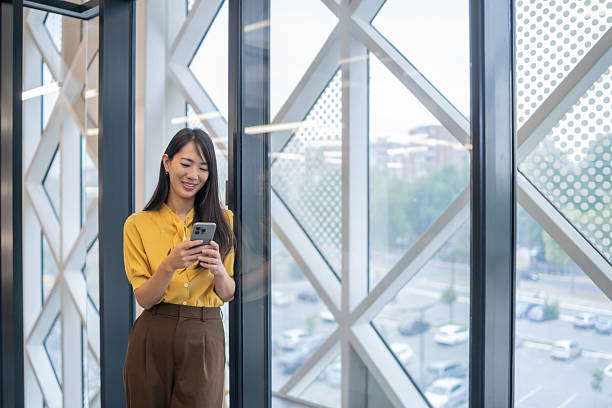 istock Young asian businesswoman using smartphone in modern office building 2240020844
