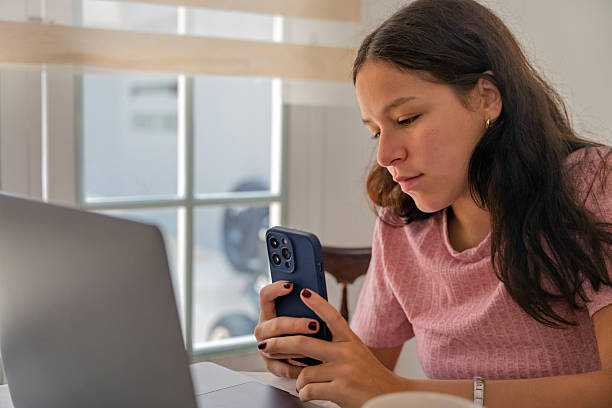 istock Young woman using phone studying remote from home 2240021269