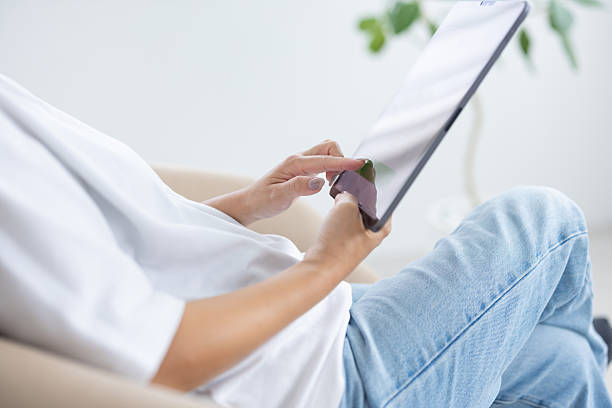 istock Young woman working on laptop while sitting on chair in bright room 2240024710