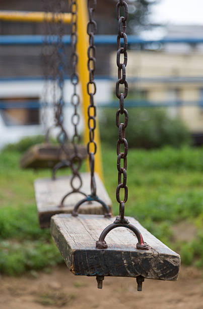Photograph of several unoccupied swings with focus on the foreground