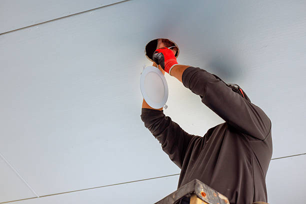 istock Electrician installing ceiling light fixture in commercial space during daytime work hours 2240034637