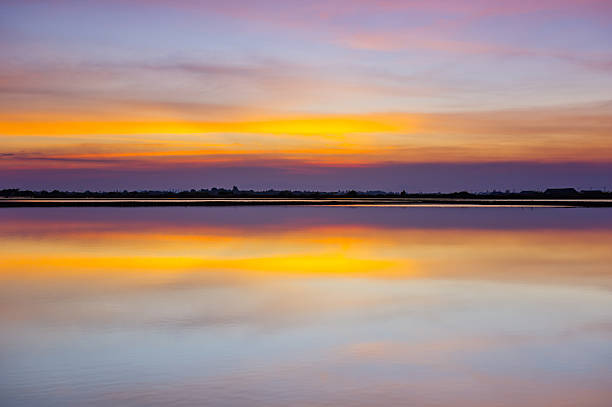 istock Spectacular Twilight Sky with Vibrant Colors and Dramatic Clouds perfectly Reflected on Calm Water or Lake Surface. Serene Landscape at Dusk or Dawn. 2240035345