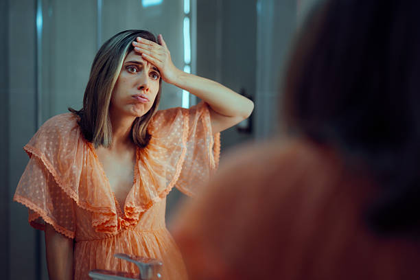 istock Upset Woman with a Hand on her Forehead Looking in the Mirror 2240039502
