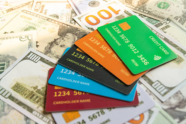 Studio shot of multiple credit cards placed over assorted US dollar banknotes, symbolizing modern payment methods and financial transactions. The image represents concepts such as online payments, global economy, personal finance, and digital banking. Ideal for illustrating topics related to commerce, cashless society, and financial technology.