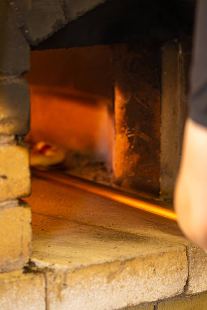 A traditional brick oven with a pizza being baked inside, capturing the warm glow and rustic ambiance of authentic wood-fired cooking