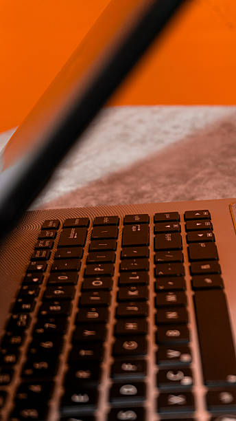 istock Open laptop on desk with vibrant orange background, modern workspace concept highlighting creativity, technology, and digital lifestyle. 2240043779
