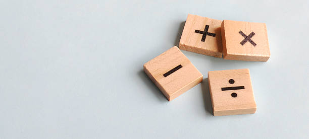 istock Fundamental arithmetic symbols on scattered wooden blocks against a soft blue background with clean copy space for educational and financial themes. 2240046050
