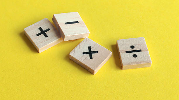 istock Scattered wooden blocks with fundamental math symbols on a bright yellow background, representing education, growth, and financial decisions. 2240046751