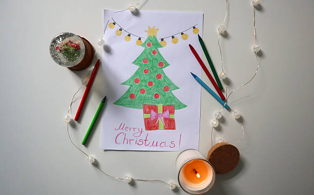 istock Hand drawn Christmas tree with red ornaments gift box, surrounded by colored pencils, snow globe, candle, fairy lights. 2240050754