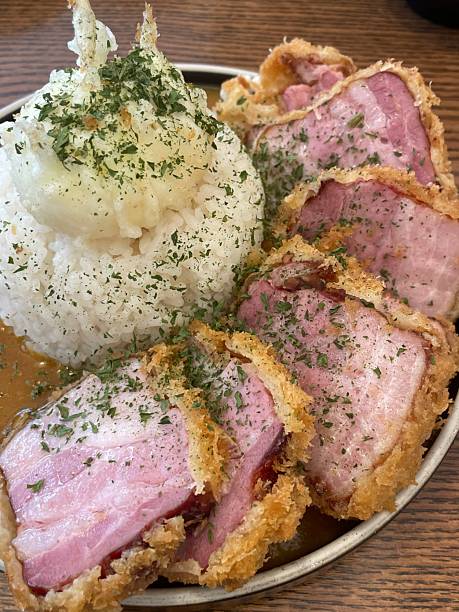 Crispy tonkatsu, a Japanese-style breaded and deep-fried pork cutlet, served with shredded cabbage and drizzled with savory sauce. A delightful balance of crunchy texture and juicy meat.
