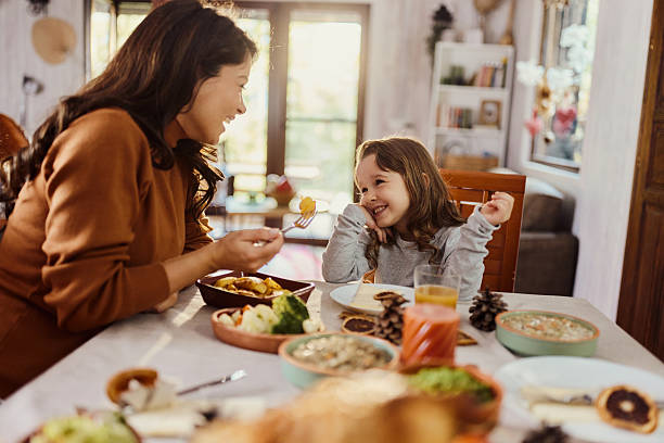 istock Happy mother and daughter talking during a meal at dining table. 2240057995