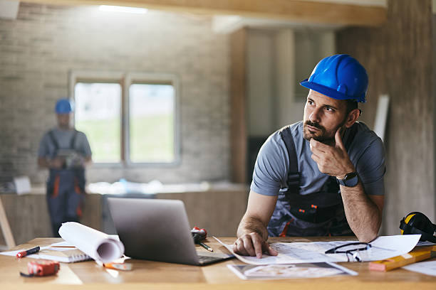 istock Pensive manual worker working on plans at renovating house. 2240058250
