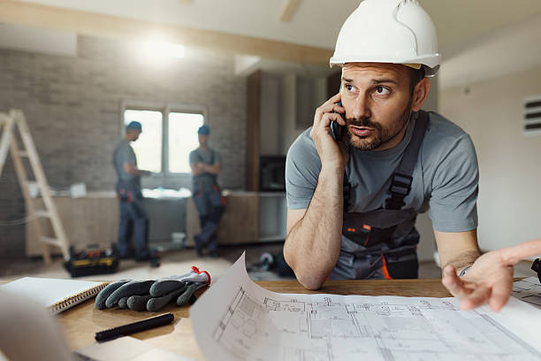 istock Displeased manual worker talking on cell phone during home renovation process. 2240058488