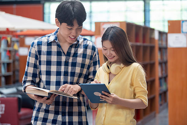 istock Group of students studying together in library. Two Asian students learning and discussing in a library at the university. 2240058521