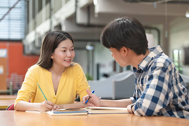 istock Group of students studying together in library. Two Asian students learning and discussing in a library at the university. 2240058543