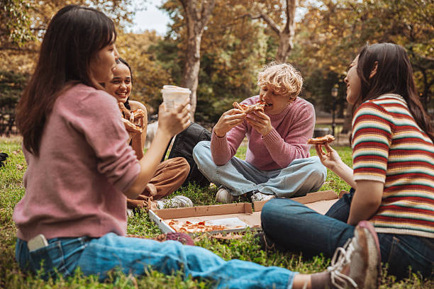 istock Four friends chillin’ in Central Park with pizza 2240058972