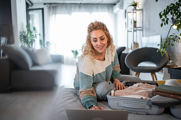 istock Woman packing suitcase and planning trip using laptop 2240059703