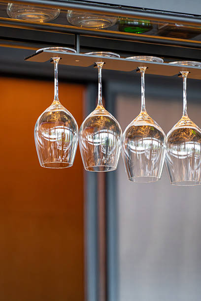 Elegant Wine Glasses Hanging Upside Down from a Rack in a Modern Bar Setting