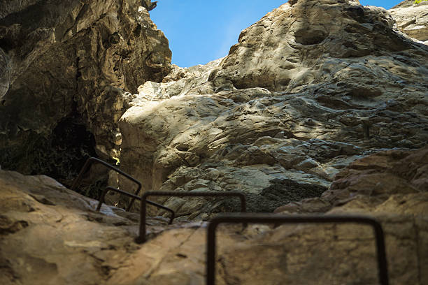 istock ​A dramatic, low-angle shot looking up and out from inside a cave or deep rock crevice towards the bright blue sky 2240062091