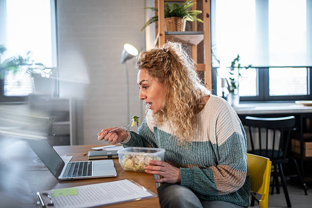 istock Woman eating salad while working on laptop 2240062975