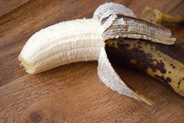 istock Brown banana with half peeled skin on table, perfect inside 2240065017