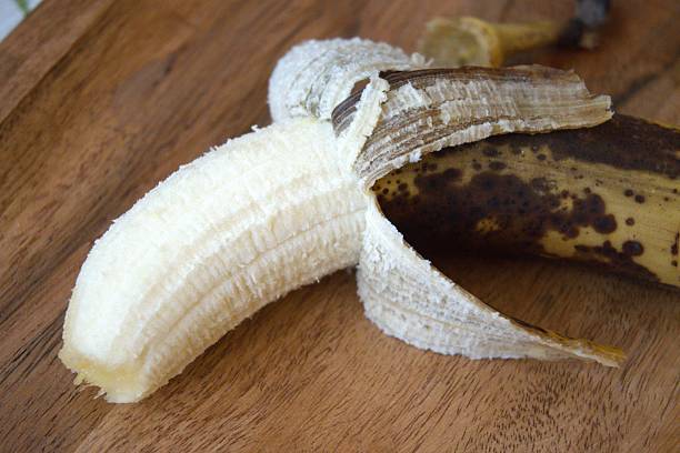 istock Brown banana with half peeled skin on table, perfect inside 2240065033