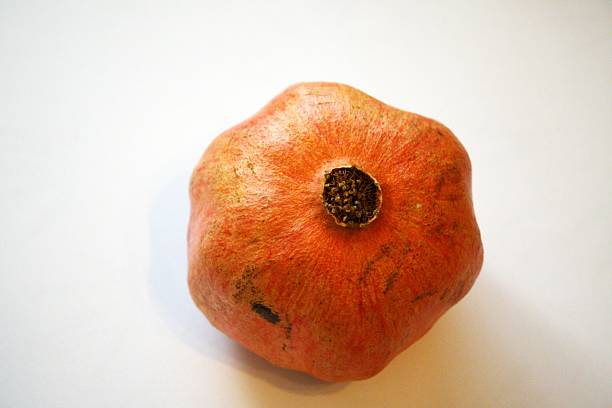 One whole pomegranate on white background with copy space. Minimal natural condition fruit photo symbolizing health and freshness.