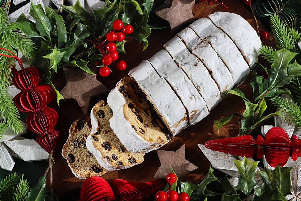 Stock photo shows a traditional German stollen, a festive Christmas fruit bread loaf dusted with icing sugar and filled with dried fruits and aromatic spices. Perfect for holiday celebrations, seasonal gatherings, and festive food photography, this classic dessert highlights German Christmas traditions