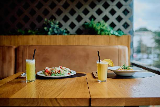 Restaurant table serving fresh green salads and healthy fruit juices, ready for a nutritious lunch or dinner inside a cafe